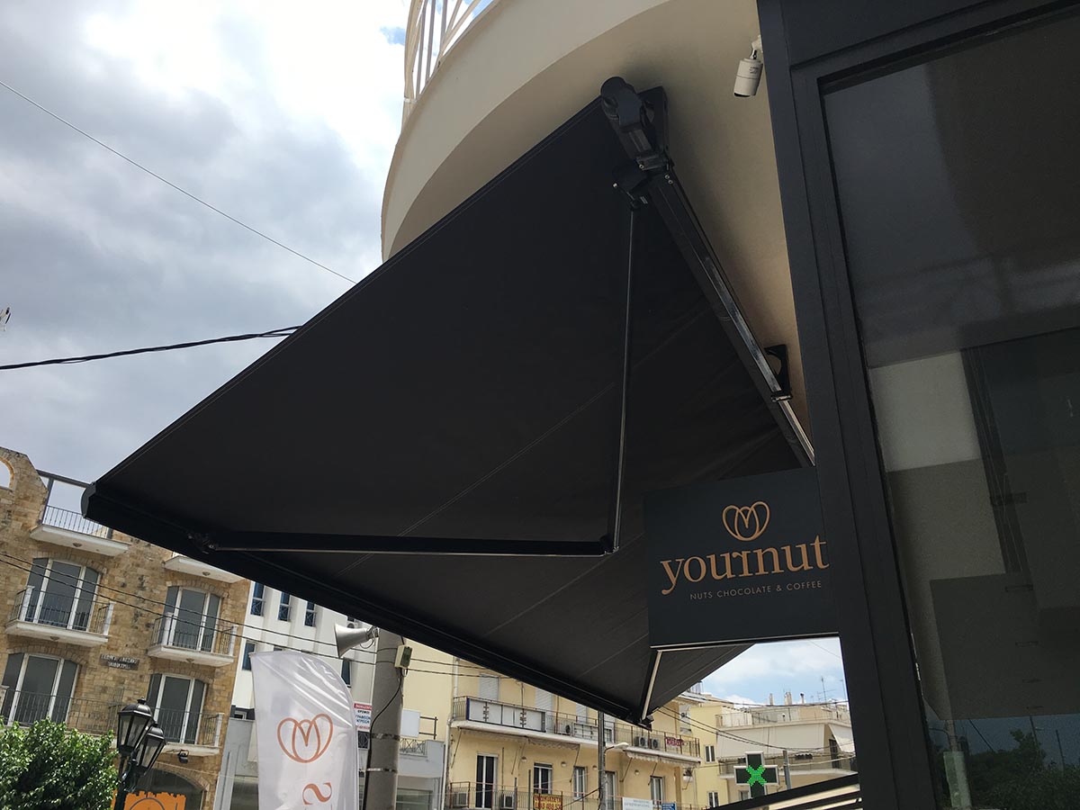 Τέντα με βραχίονες σε σύστημα μπάρας με μοτέρ σε καφέ στην περιοχή της νέας Ερυθραίας